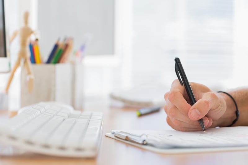 Close up of a hand writing in a modern office on a clipboard.jpeg