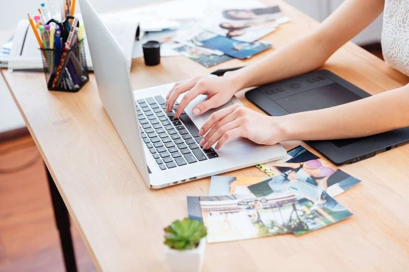 Closeup of hands of young woman photograper typing on laptop keyboard and using graphic tablet.jpeg