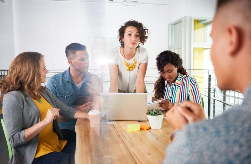 Multi ethnic group of succesful creative business people using a laptop during candid meeting.jpeg