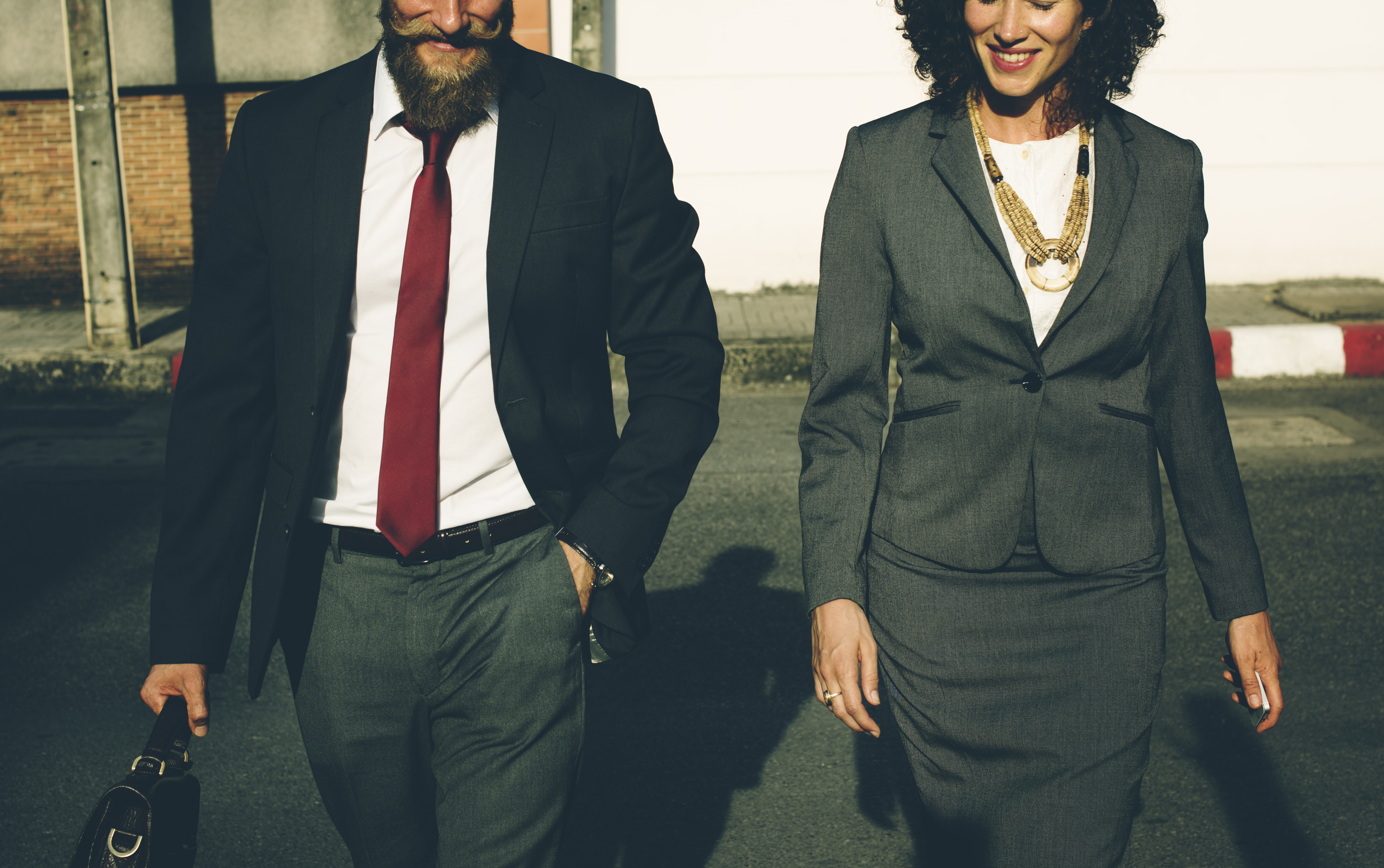 Bearded man in red tie and woman in business suit walking to work.